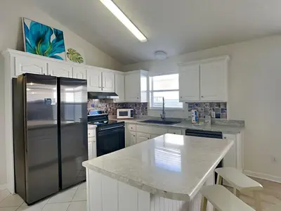 a kitchen with white cabinets and a stainless steel refrigerator at Captain Bennetts Cove in Panama City Beach
