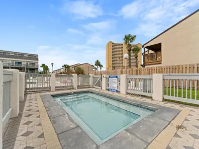 a swimming pool with a fence and a building at Endless Summer #A30 in Panama City Beach