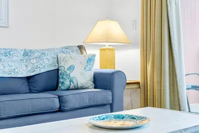 a living room with a blue couch and a table at Beachfront, Ocean Views, Sleeps 6 , Hot tub in Panama City Beach