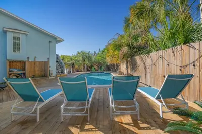 a patio with chairs and a table and a pool at Latitude Adjustment - Private Pool, Game Room, Spacious Home, Pets OK, 5 Min Walk to Beach! in Panama City Beach