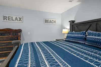 a bedroom with a bed with blue comforter and blue pillows at Latitude Adjustment - Private Pool, Game Room, Spacious Home, Pets OK, 5 Min Walk to Beach! in Panama City Beach
