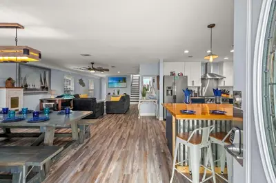 a kitchen and a living room with a table and a kitchen at Latitude Adjustment - Private Pool, Game Room, Spacious Home, Pets OK, 5 Min Walk to Beach! in Panama City Beach