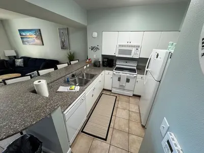 a kitchen with white appliances and a living room at SHORES of PANAMA 315 in Panama City Beach