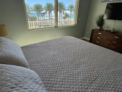 a bedroom with a bed and a window with palm trees at SHORES of PANAMA 315 in Panama City Beach