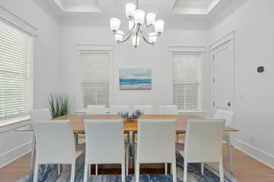 a dining room with a wooden table and white chairs at Sea Esta Villa in Santa Rosa Beach