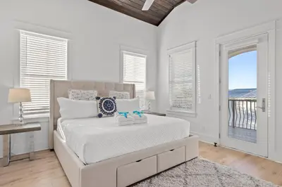 a white bedroom with a large bed and windows at Sea Esta Villa in Santa Rosa Beach