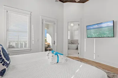 a white bedroom with a bed and a tv on the wall at Sea Esta Villa in Santa Rosa Beach