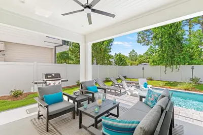 a patio with a couch and chairs and a pool at The Suite Life on 30A in Santa Rosa Beach