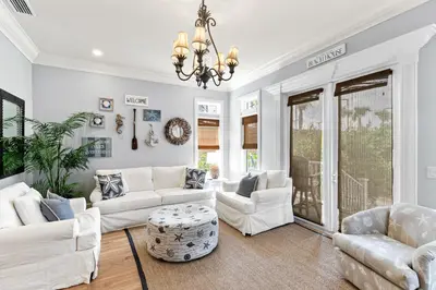 a living room with white furniture and a chandelier at Big Kahuna Beach House in Santa Rosa Beach