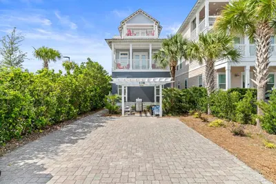 a white house with palm trees and a driveway at Big Kahuna Beach House in Santa Rosa Beach