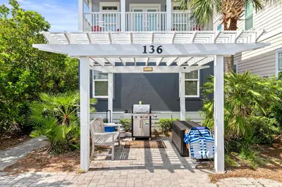 a white pergola with a table and chairs on a patio at Big Kahuna Beach House in Santa Rosa Beach