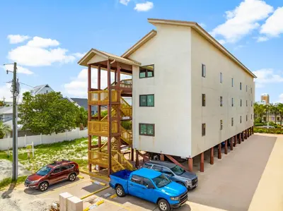 a building with two cars parked in front of it at Location! Studio Condo Panama City Beach, Holiday Beach, Tents Allowed! in Panama City Beach