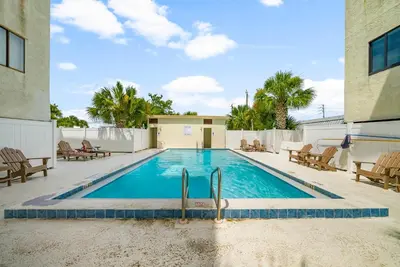 a swimming pool with chairs and a building at Location! Studio Condo Panama City Beach, Holiday Beach, Tents Allowed! in Panama City Beach