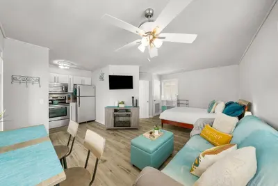 a living room with a blue couch and a bed at Location! Studio Condo Panama City Beach, Holiday Beach, Tents Allowed! in Panama City Beach
