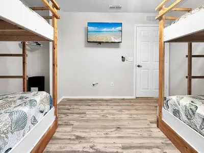a bedroom with two bunk beds and a flat screen tv at Kid's Playground & Pool! | Spring Getaway! in Panama City Beach