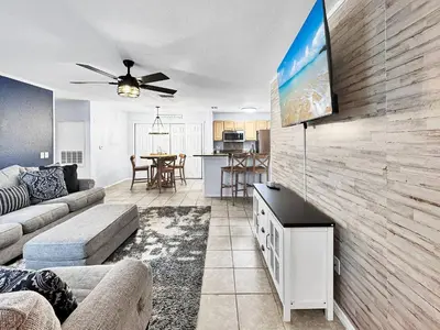 a living room with a couch and a tv on a wall at Kid's Playground & Pool! | Spring Getaway! in Panama City Beach