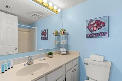a bathroom with a sink and a toilet and a mirror at Commodore 1306 in Panama City Beach
