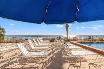 a row of chairs and an umbrella on a beach at Commodore 1306 in Panama City Beach