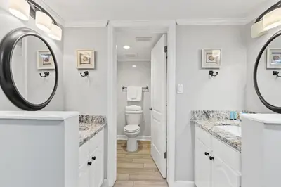 a white bathroom with a toilet and a mirror at Commodore 1106 in Panama City Beach