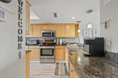 a kitchen with wooden cabinets and stainless steel appliances at Commodore 1106 in Panama City Beach