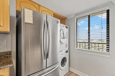 a kitchen with a refrigerator and a washer and dryer at Commodore 1106 in Panama City Beach