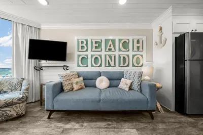 a living room with a blue couch and a tv at Beachfront Studio Condo - Top of the Gulf 317 in Panama City Beach