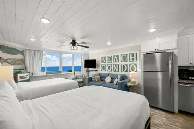 a bedroom with two beds and a refrigerator at Beachfront Studio Condo - Top of the Gulf 317 in Panama City Beach