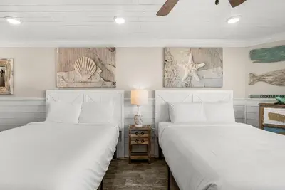 two beds in a bedroom with white walls at Beachfront Studio Condo - Top of the Gulf 317 in Panama City Beach