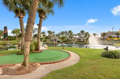 a golf course in a park with palm trees and a fountain at It Doesn’t Get Any Better Than This! 2BR 2BA Sleeps 8 Beachfront! in Panama City Beach