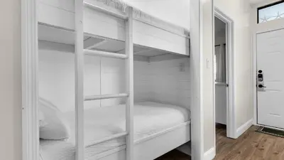a white bedroom with bunk beds in it at Palms B4 in Santa Rosa Beach