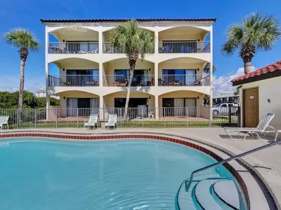 a swimming pool in front of a building with palm trees at Palms B4 in Santa Rosa Beach