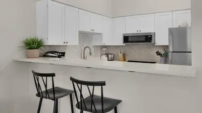 a kitchen with white cabinets and two black bar stools at Palms B4 in Santa Rosa Beach