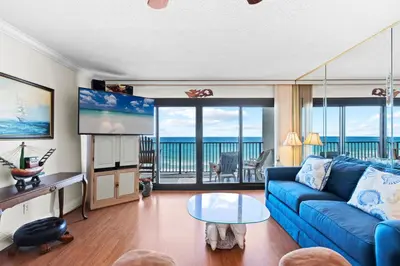 a living room with a blue couch and a view of the ocean at Commodore 0608 in Panama City Beach