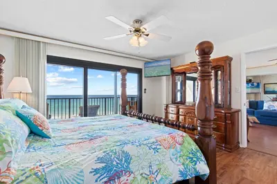 a bedroom with a bed and a view of the ocean at Commodore 0608 in Panama City Beach