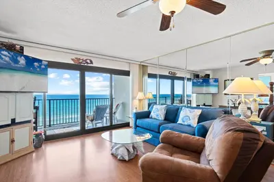 a living room with a blue couch and a view of the ocean at Commodore 0608 in Panama City Beach