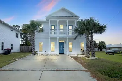 a white house with two palm trees in front of it at Sunny Daze by Emerald Coast Retreats in Panama City Beach