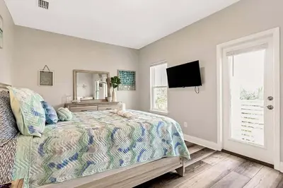 a bedroom with a bed and a mirror and a tv at Sunny Daze by Emerald Coast Retreats in Panama City Beach