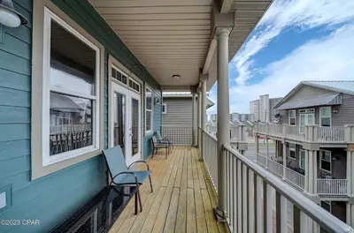 a porch of a blue house with chairs on it at Blue Lagoon by Emerald Coast Retreats in Panama City Beach