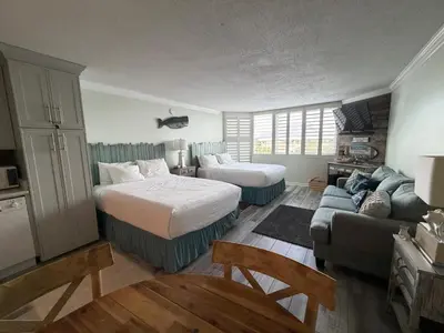a hotel room with two beds and a couch at Renovated Beach Front Condo - Top of the Gulf 302 in Panama City Beach