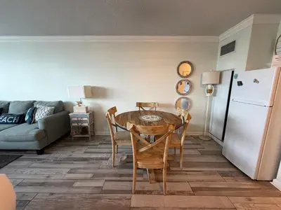 a living room with a table and a white refrigerator at Renovated Beach Front Condo - Top of the Gulf 302 in Panama City Beach