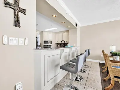 a kitchen with a bar with chairs and a table at Hidden Dunes 704 in Panama City Beach