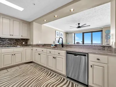 a kitchen with white cabinets and a rug at Hidden Dunes 704 in Panama City Beach