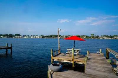 a dock with a table and an umbrella on the water at Lagoon Landing Waterfront Home in Panama City Beach