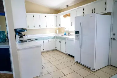 a kitchen with white cabinets and a white refrigerator at Lagoon Landing Waterfront Home in Panama City Beach