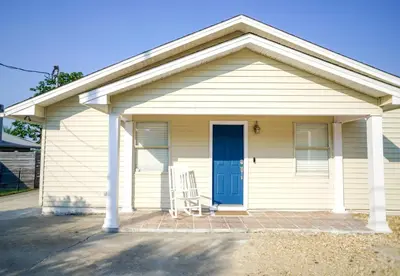 a small white house with a blue door at Lagoon Landing Waterfront Home in Panama City Beach