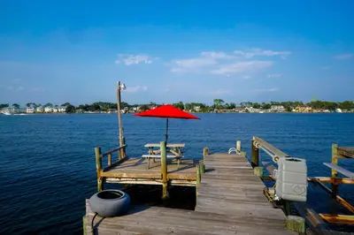 a wooden dock with a table and an umbrella on the water at Lagoon Landing Waterfront Home in Panama City Beach