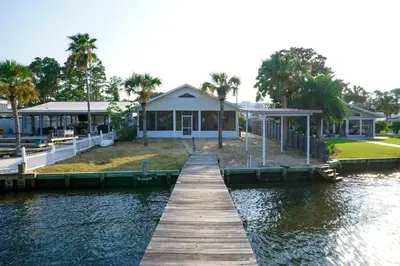 a dock in front of a house on a body of water at Lagoon Landing Waterfront Home in Panama City Beach