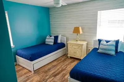 two beds in a room with blue walls at Lagoon Landing Waterfront Home in Panama City Beach