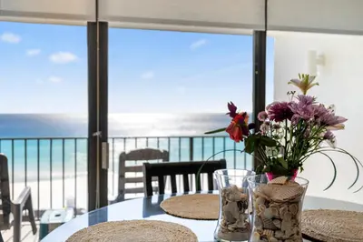 a vase of flowers on a table with a view of the ocean at 1007 Edgewater T1 Beach Resort in Panama City Beach