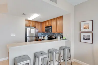 a kitchen with wooden cabinets and a counter with stools at 1202 Seychelles in Panama City Beach